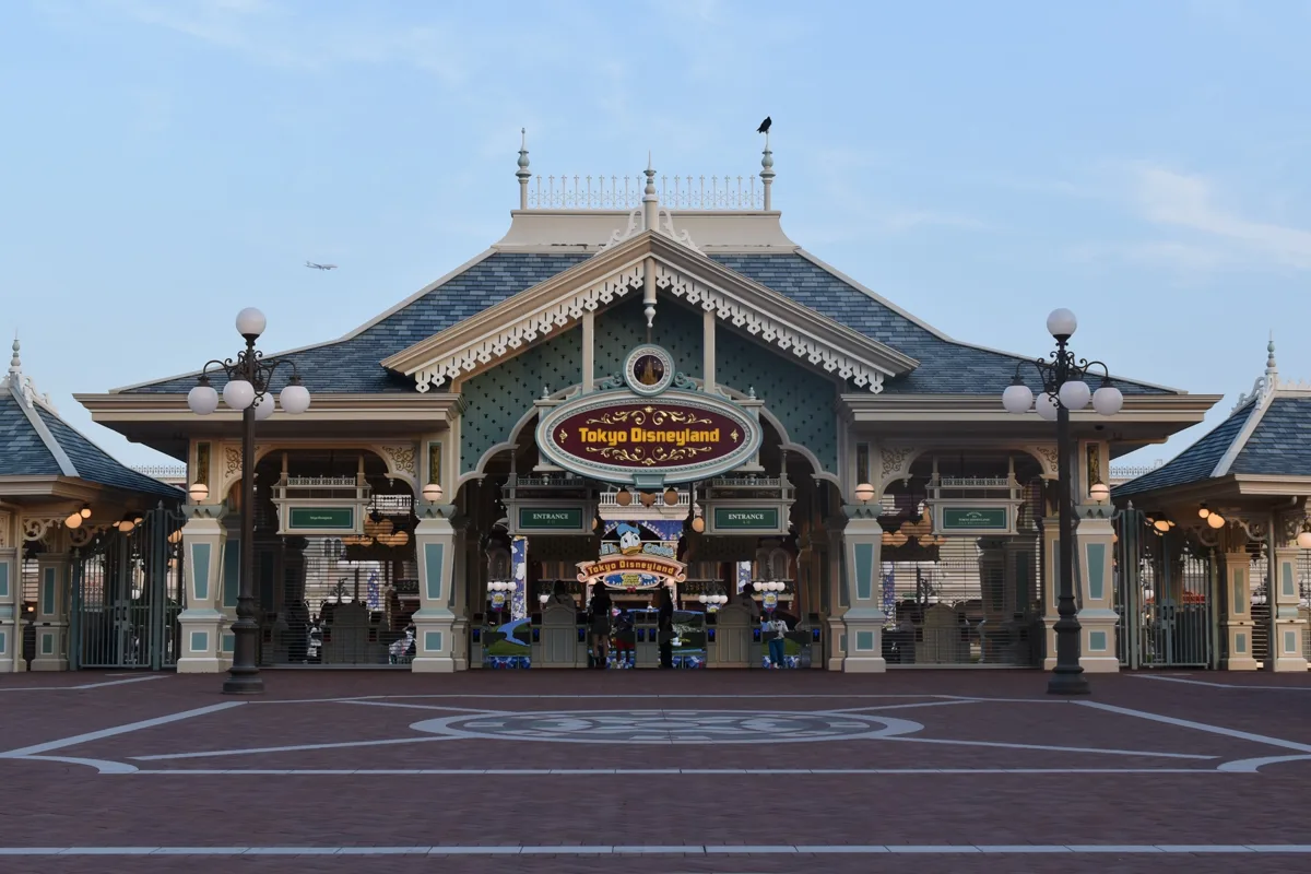 Tokyo Disneyland main entrance building with the park name sign over the gates, seen across an almost empty plaza