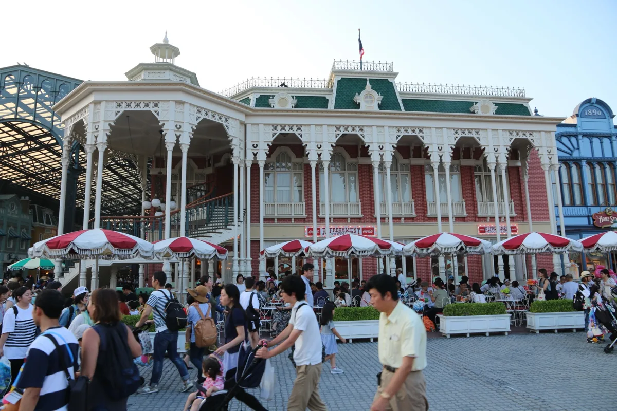 Victorian-style World Bazaar building with red parasols and visitors walking past