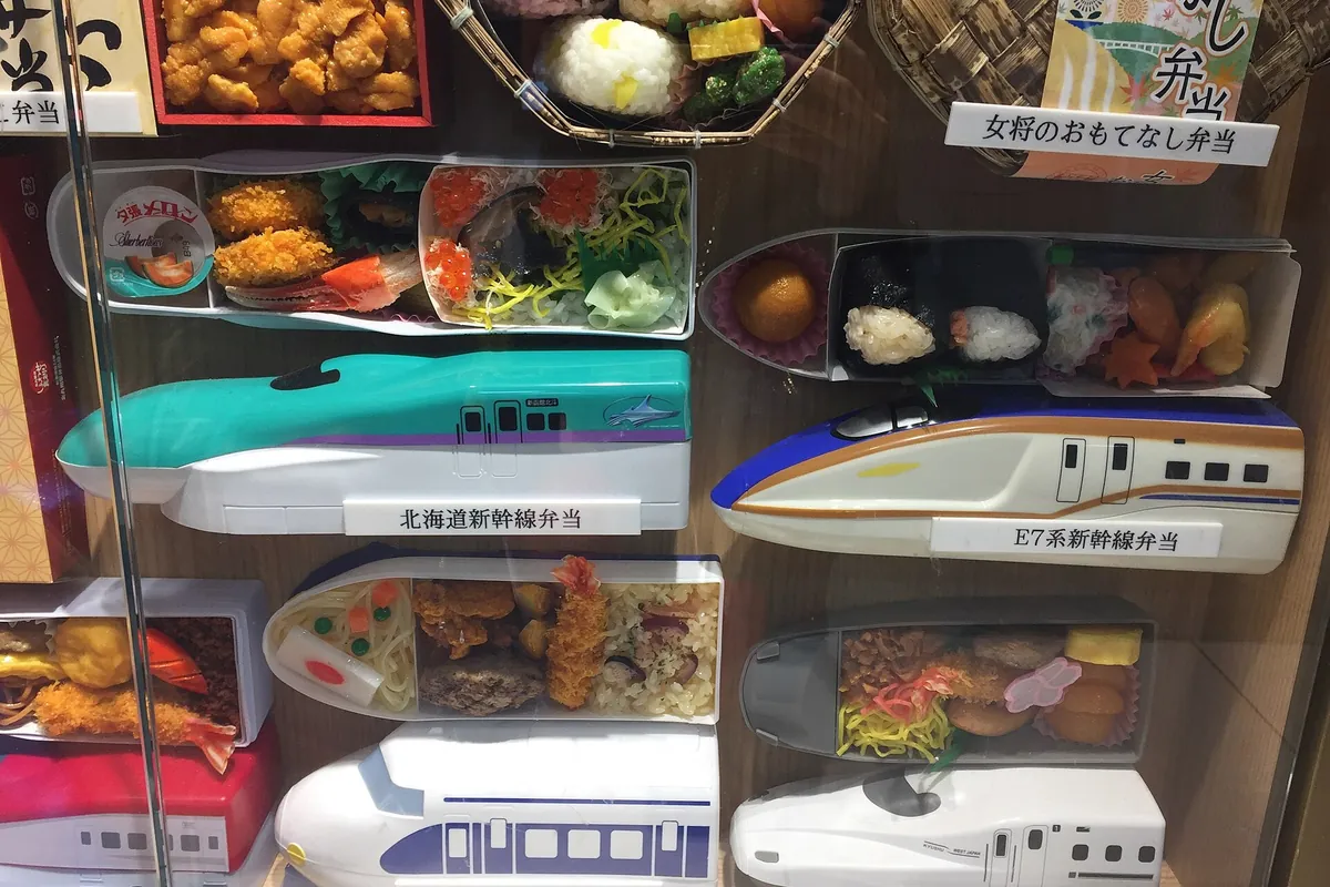 Shinkansen-shaped bento boxes displayed on a wall at an ekiben shop in Tokyo Station