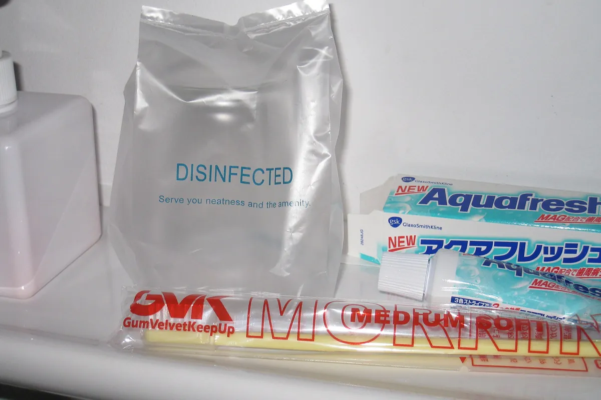 DISINFECTEDと書かれた袋やAquafreshの歯みがき粉、包装された歯ブラシなど、日本のホテルのアメニティ