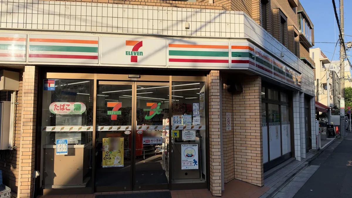 The front of a 7-Eleven store in Tokyo, with the green, orange and red stripes over the glass doors