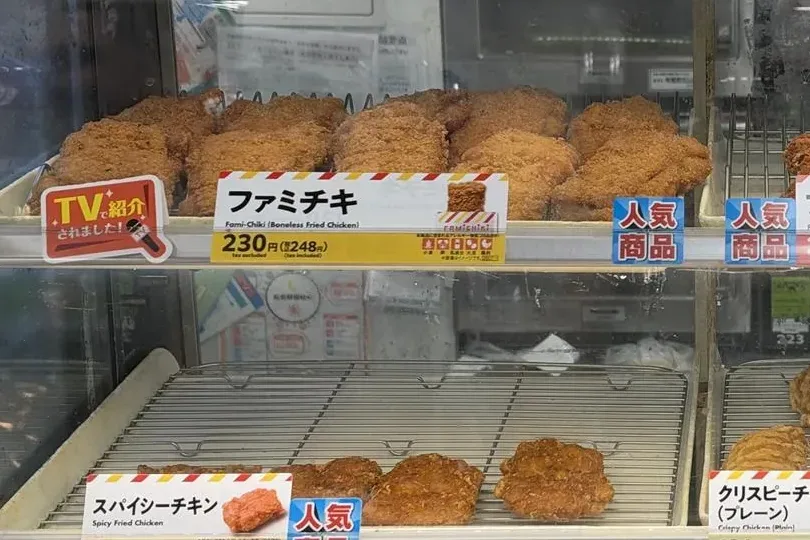 Famichiki pieces on the top shelf of a FamilyMart hot snack case in Tokyo, above a label in Japanese and English