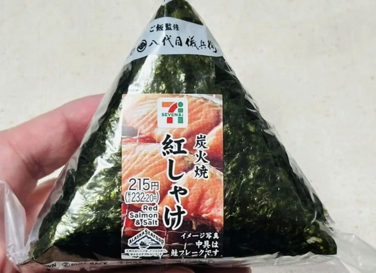 A 7-Eleven salmon onigiri in its plastic wrapper, held in a hand