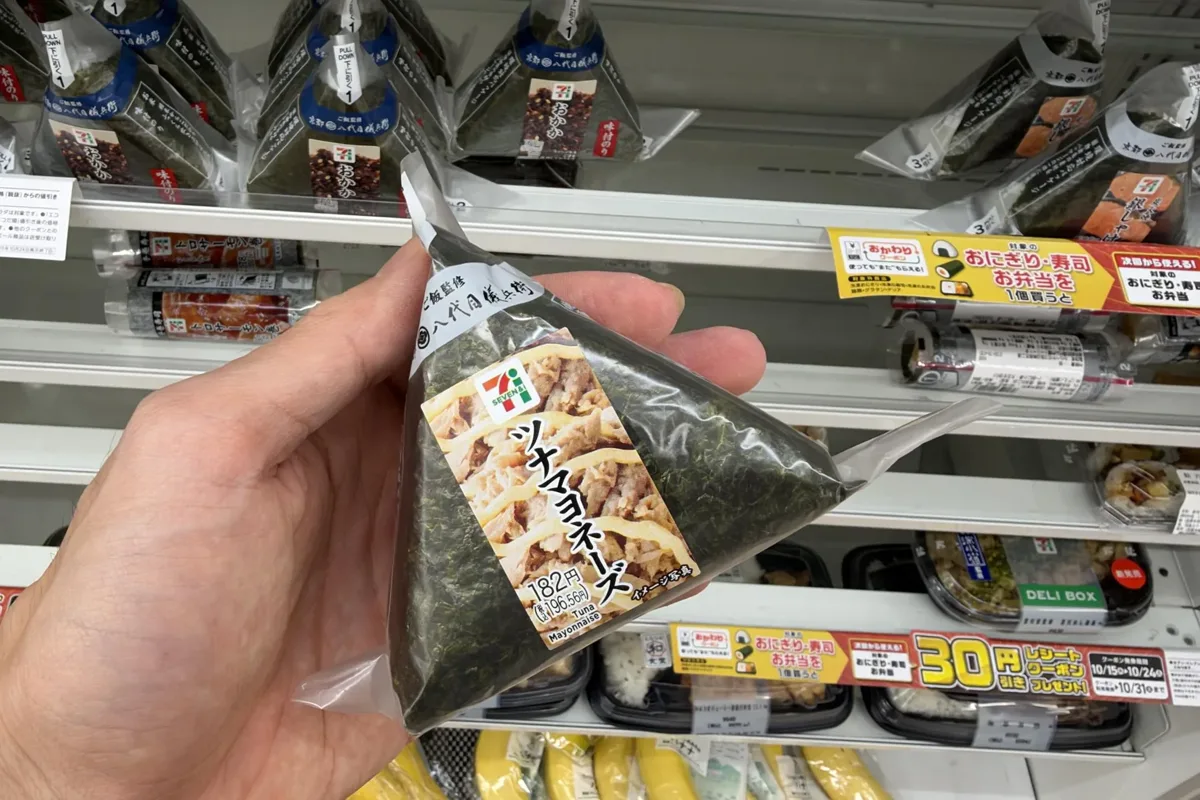 A 7-Eleven tuna mayonnaise onigiri labelled 182 yen (196.56 yen with tax) in a Tokyo store on 20 October 2026