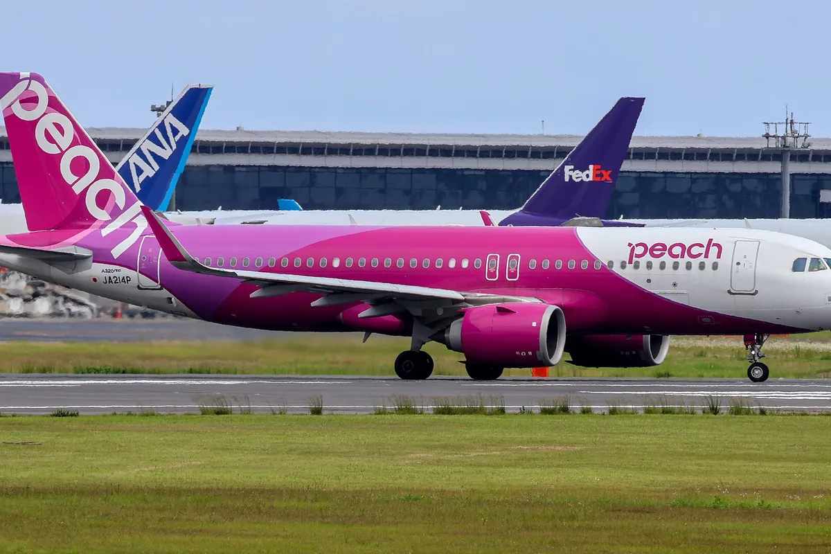Pink Peach Aviation Airbus A320 taxiing, with ANA and FedEx aircraft tails visible behind