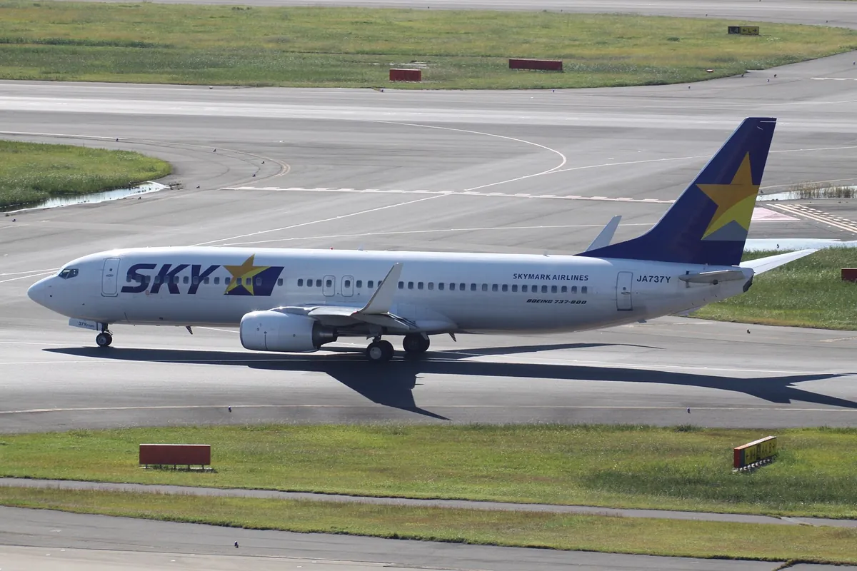 Skymark Airlines Boeing 737 in white livery with a blue tail taxiing on the runway