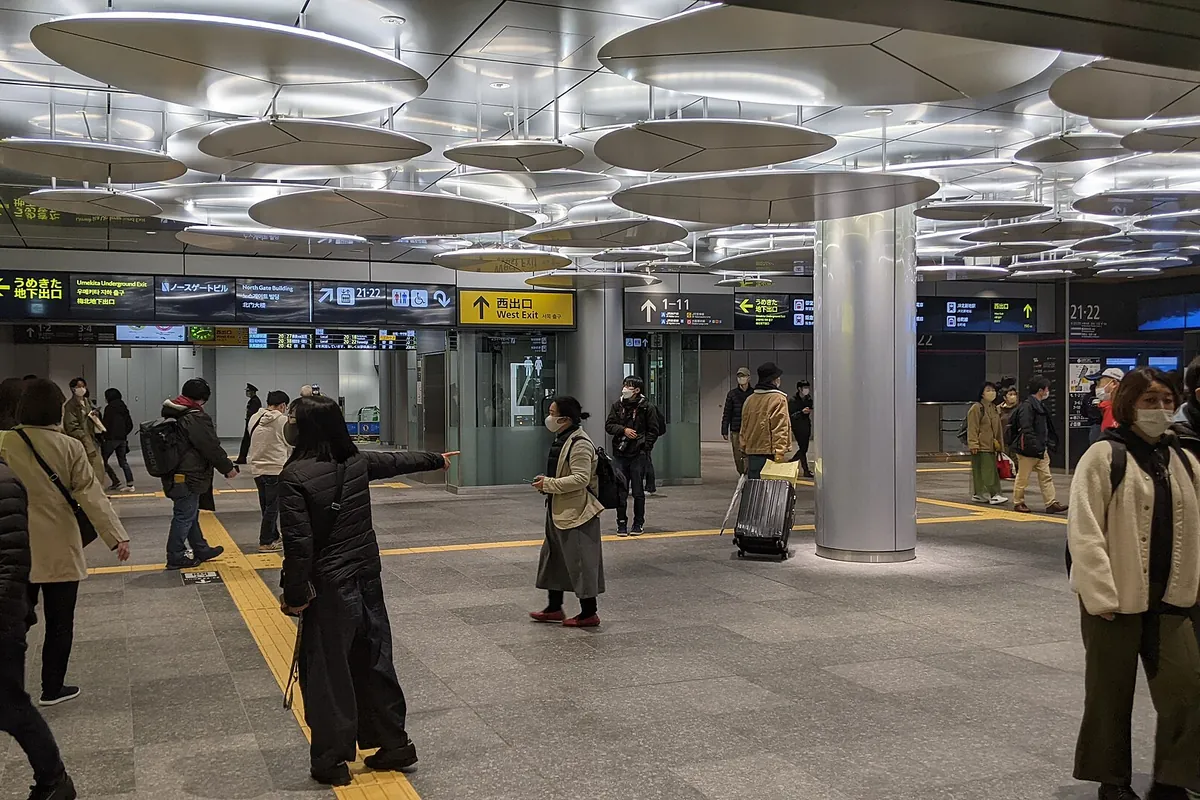 Interior of JR Osaka Station's Umekita entrance with round ceiling lights and people walking through the concourse
