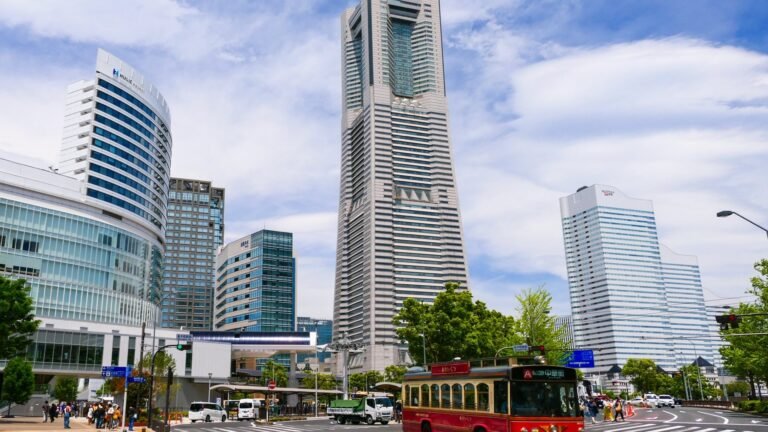 桜木町駅近く、青空の下の横浜ランドマークタワーとみなとみらい21地区、赤い観光バス