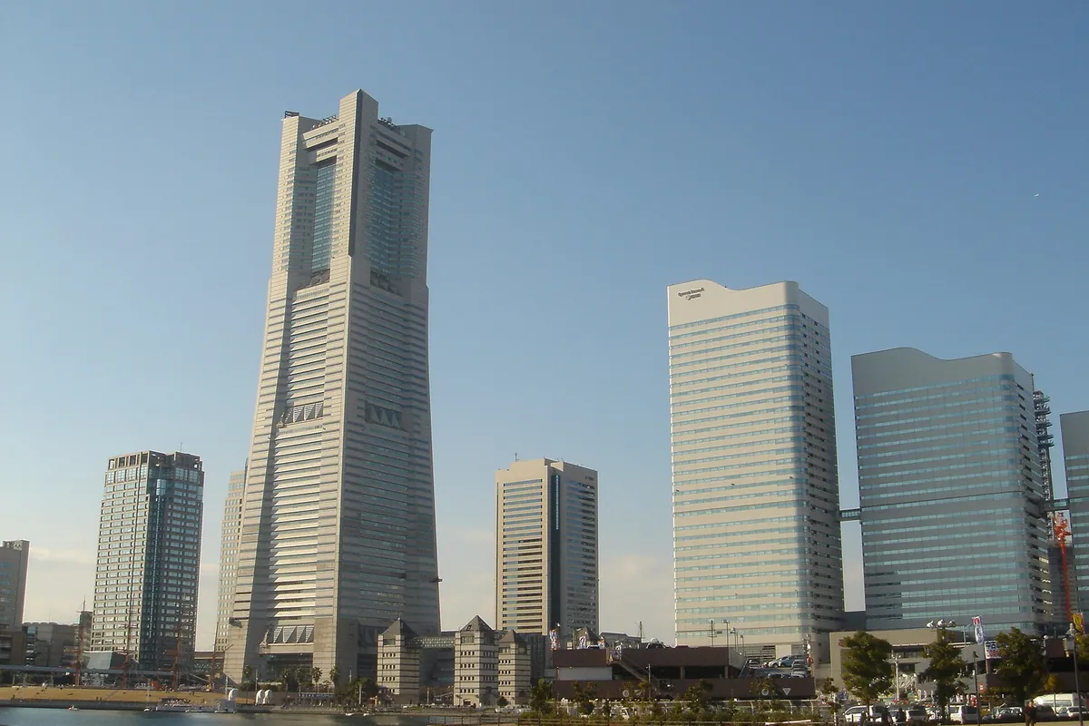 横浜ランドマークタワーとみなとみらいの高層ビル群、手前の水辺には係留された船が見える