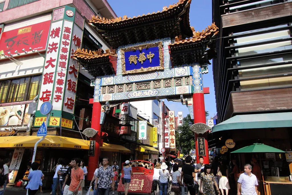 横浜中華街の通りにかかる善隣門、店の看板とその下を歩く人々の様子