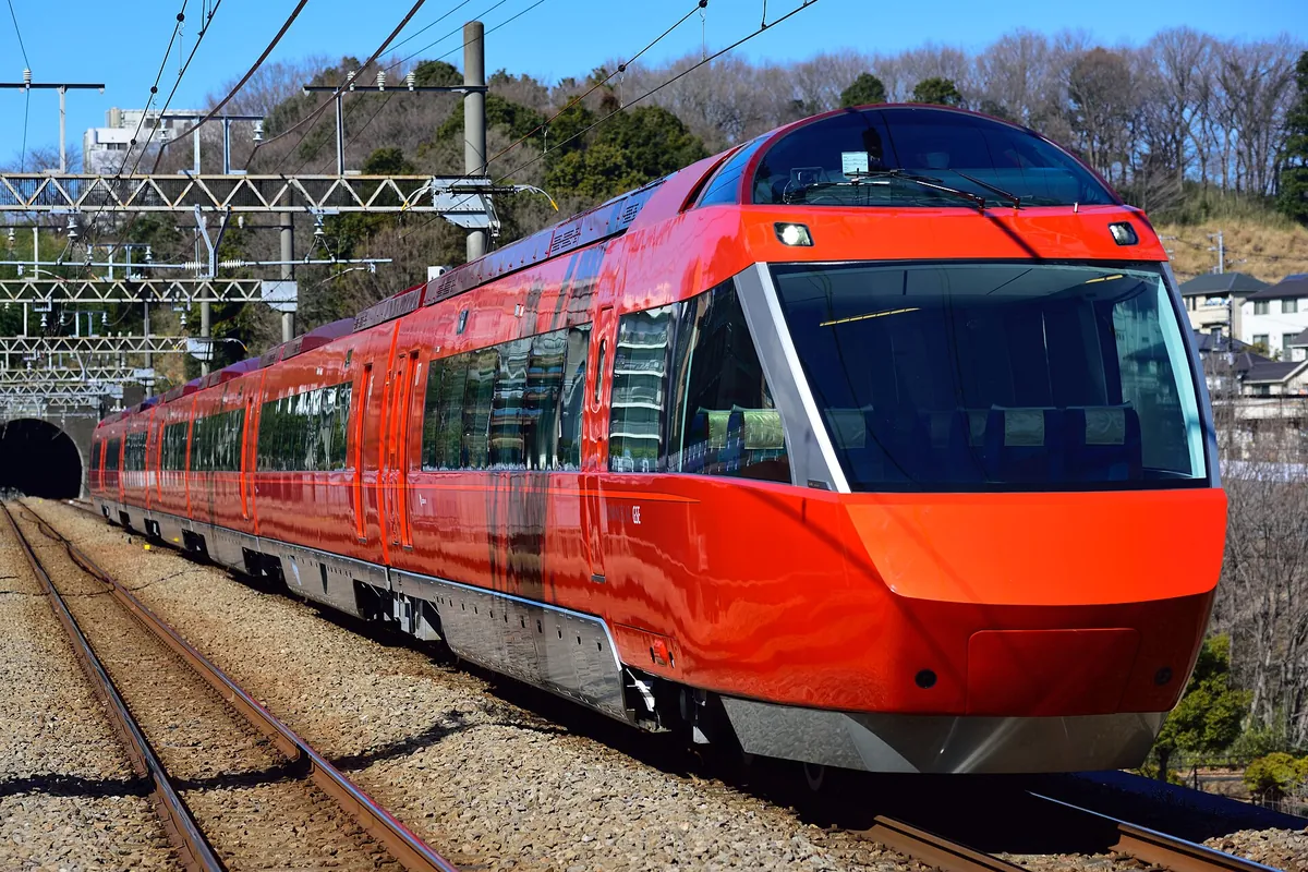 An Odakyu 70000 series GSE Romancecar limited express train in red livery running on an outdoor track in Kanagawa