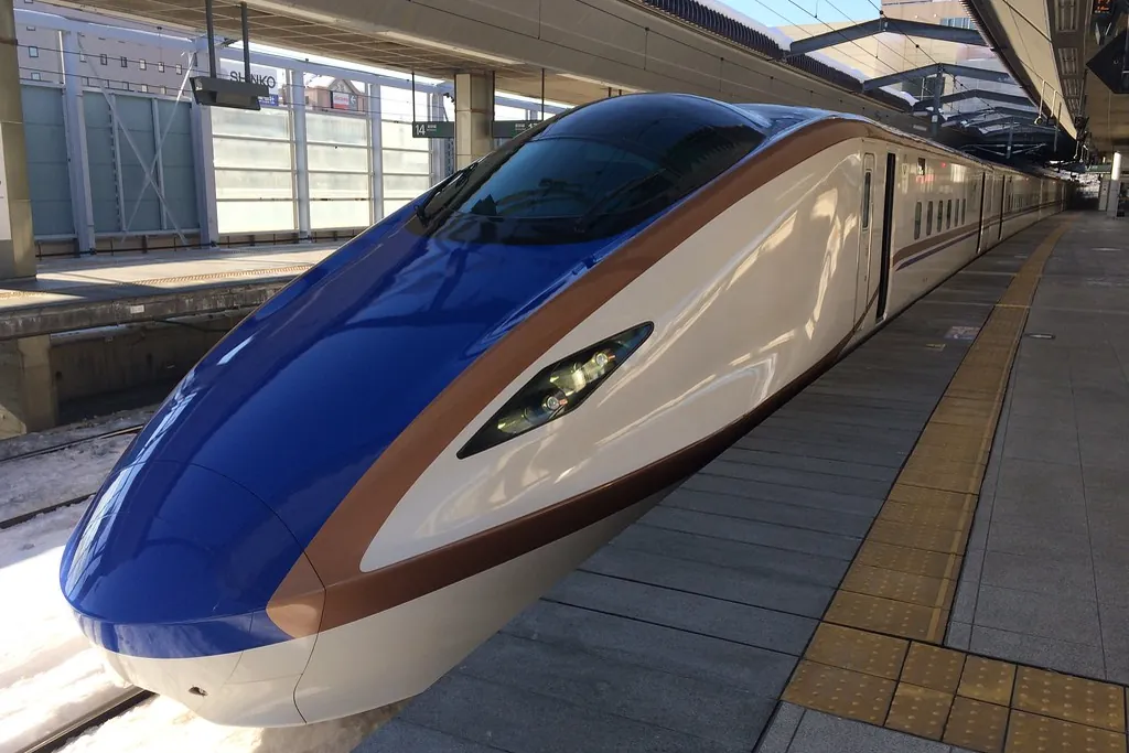 A Hokuriku Shinkansen train at a station platform in Nagano, Japan