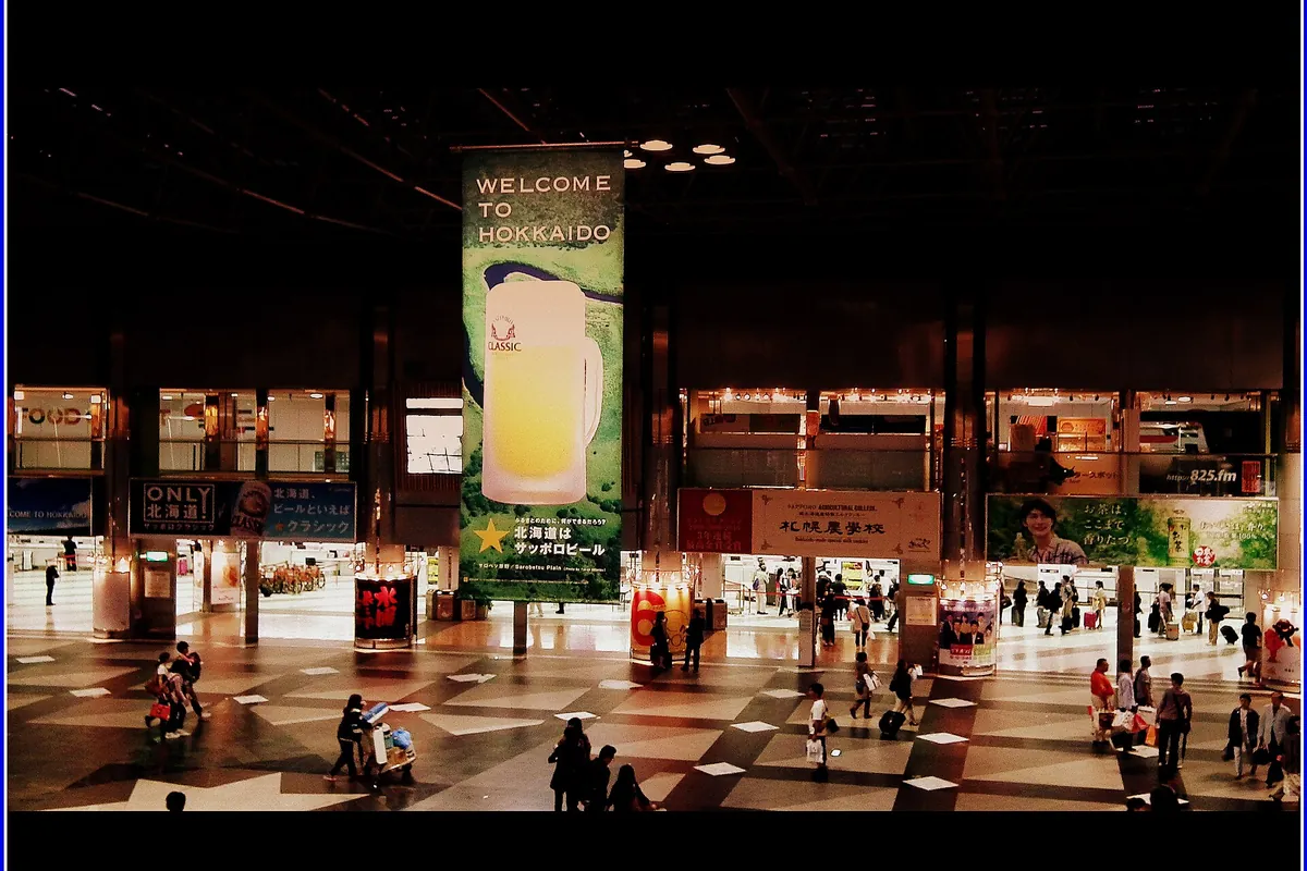 Interior of New Chitose Airport with a Welcome to Hokkaido banner and travellers walking across the floor