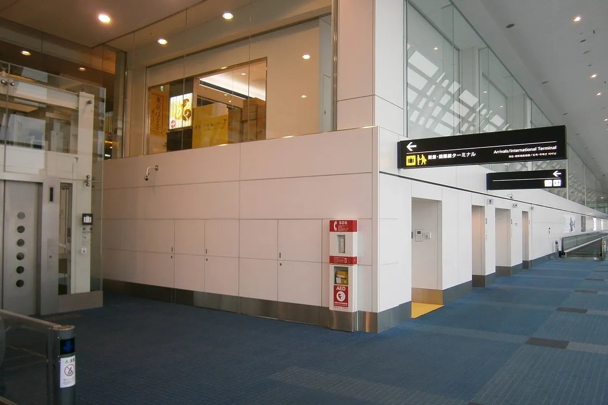 A corridor with an elevator and an Arrivals/International Terminal sign near an arrival exit at Haneda Airport