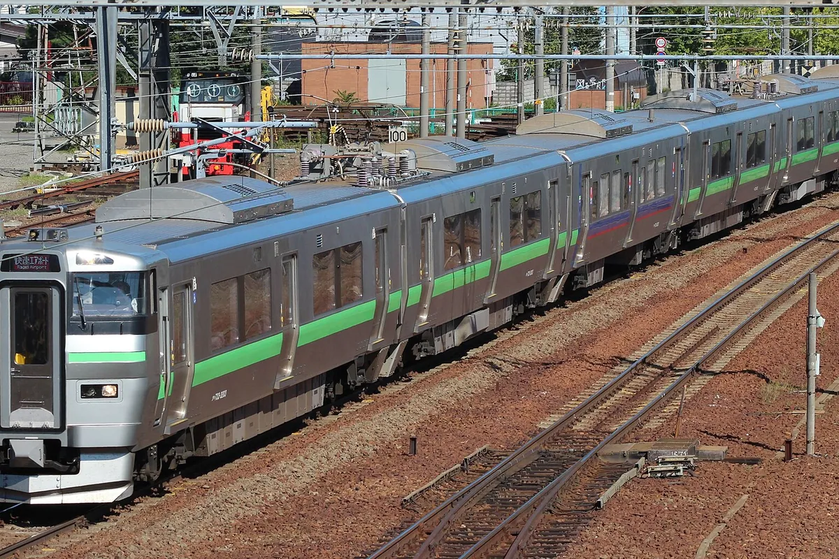 JR Hokkaido Rapid Airport train on railway tracks with overhead power lines and signal equipment