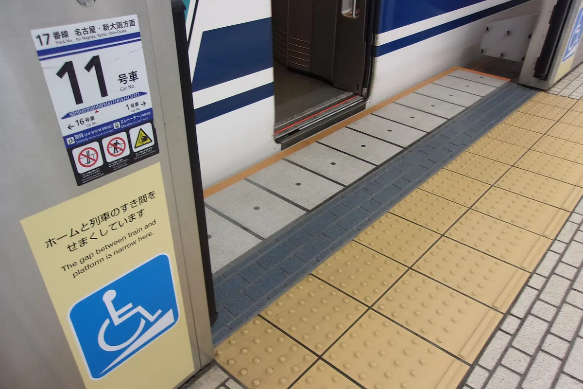 A car number "11" marker and wheelchair boarding ramp sign on a Tokaido Shinkansen platform at Tokyo Station