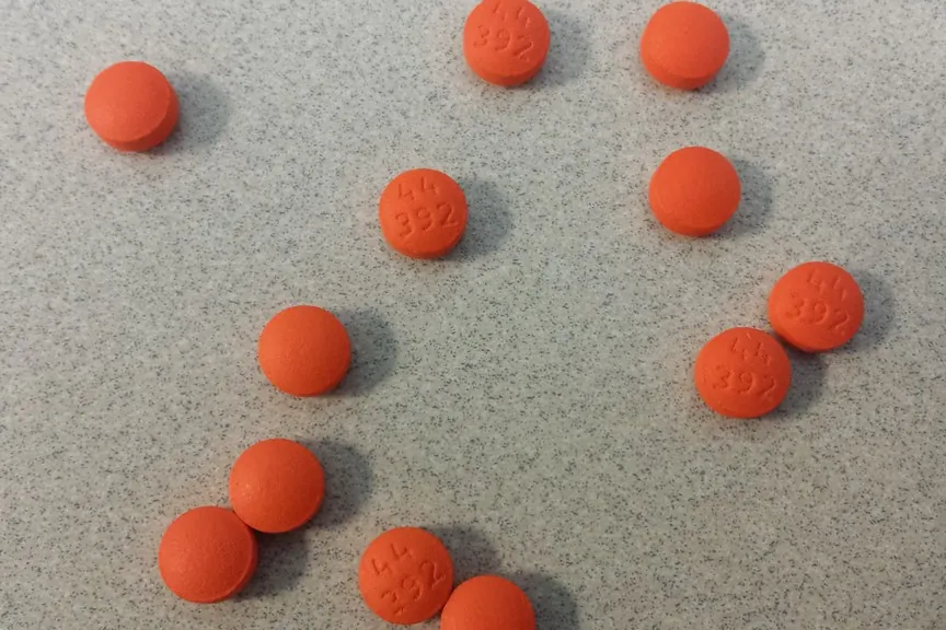 Orange tablets with imprint marks scattered on a gray countertop