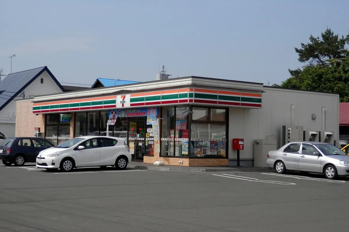 A 7-Eleven convenience store building with a parking lot and cars parked in front in Eniwa, Hokkaido, Japan