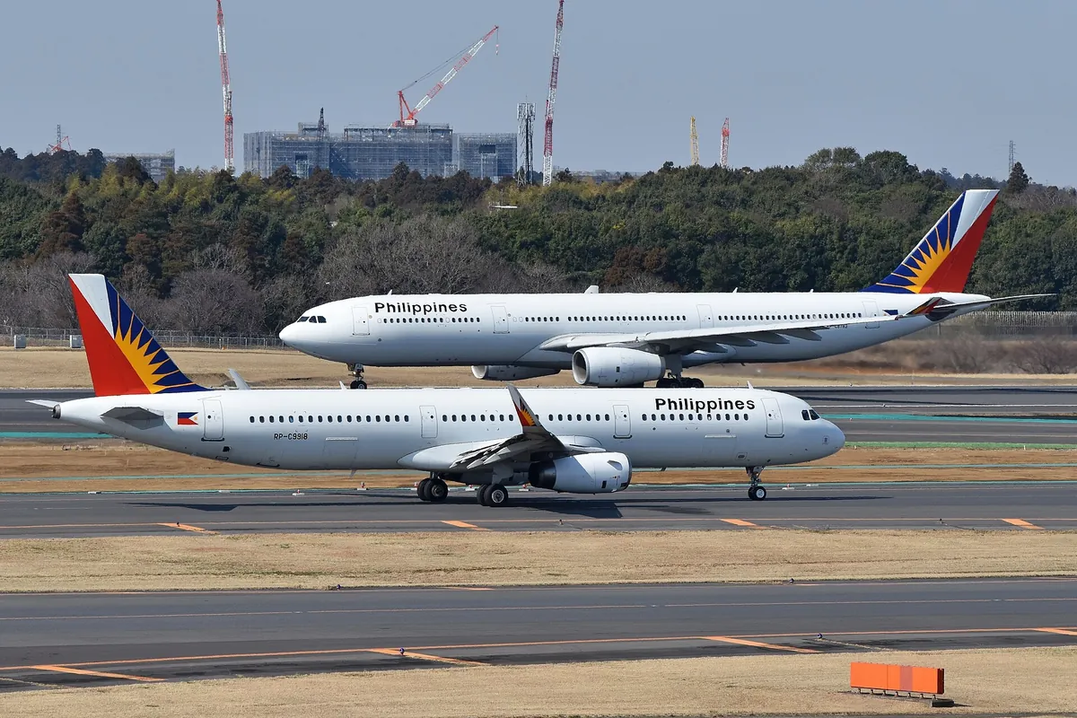 Two Philippine Airlines aircraft, an A330 and an A321, on the tarmac at Narita Airport, Japan, with trees and construction cr