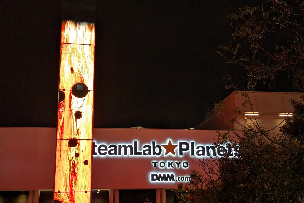 밤에 미술관 건물에 불이 켜진 teamLab Planets Tokyo 입구 간판