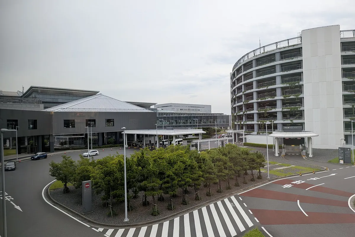 Exterior view of a terminal building at Haneda Airport with a crosswalk and multi-story parking garage in front