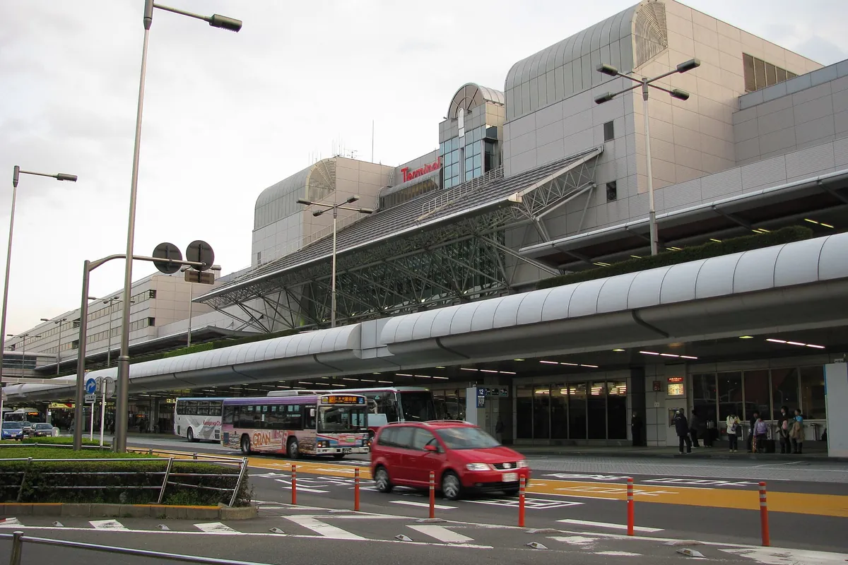 The exterior of Haneda Airport Terminal 1 with a bus and a car passing the entrance