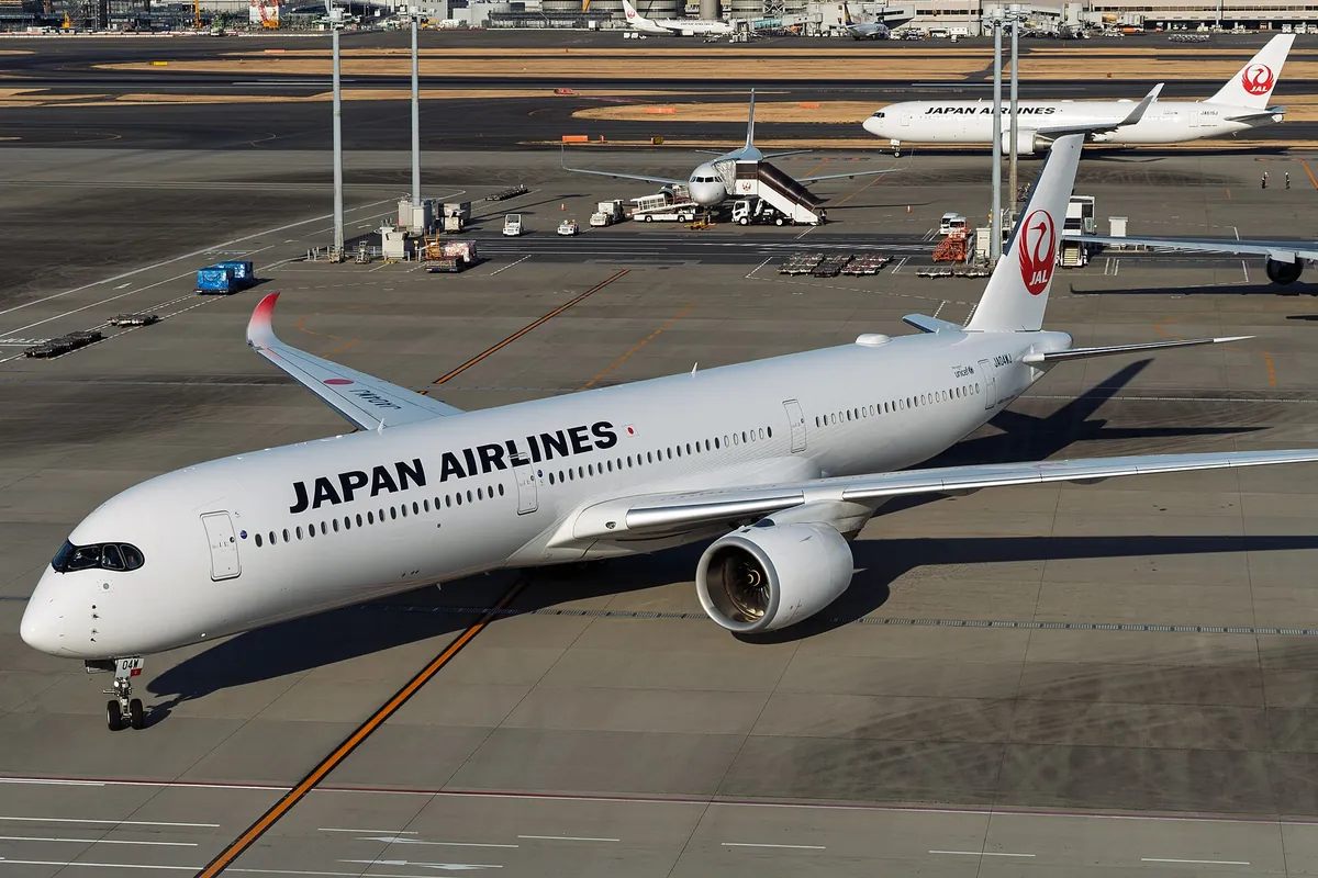 A Japan Airlines Airbus A350 on the tarmac with other JAL aircraft parked in the background