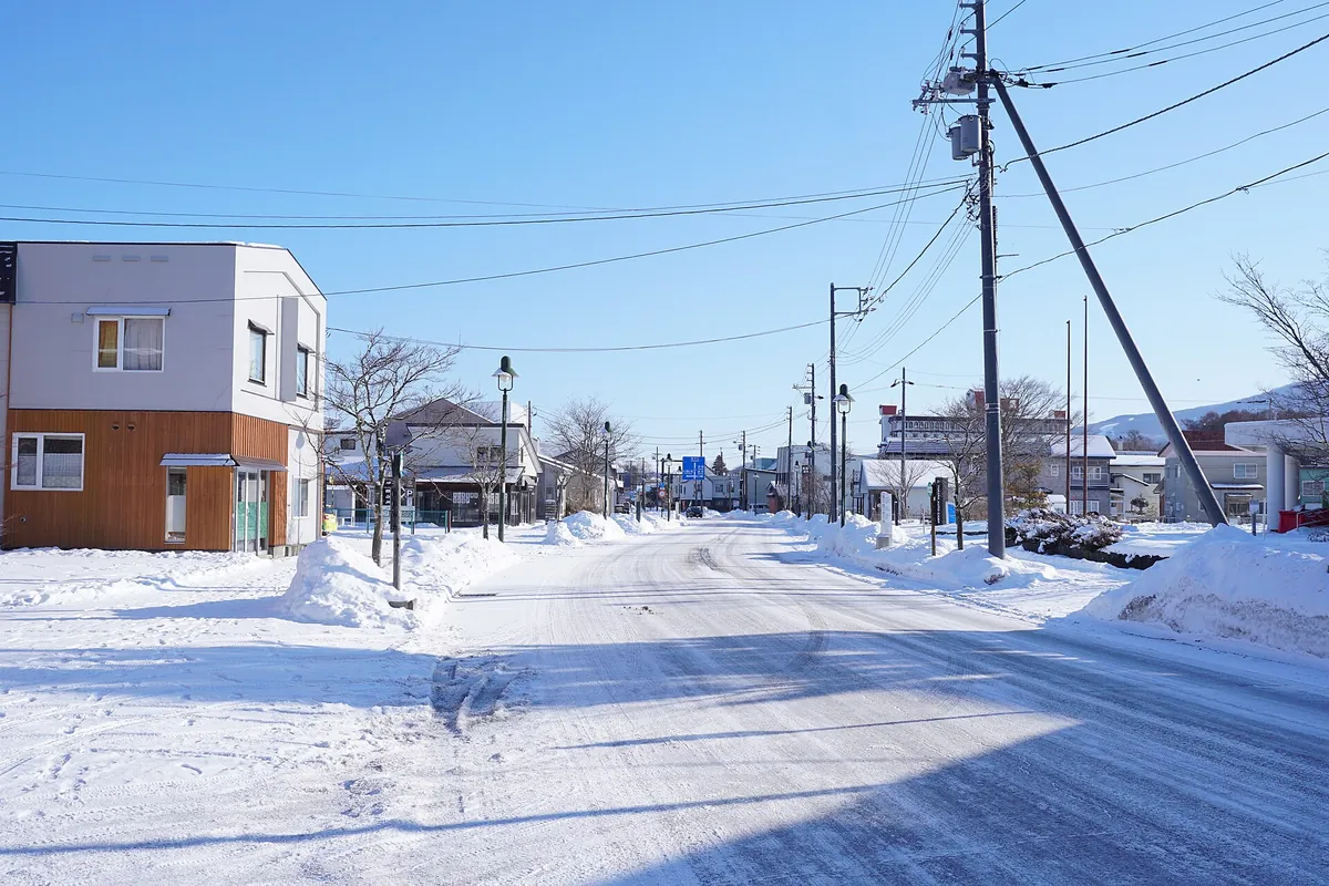 北海道七饭町被雪覆盖的街道，路边堆着高高的雪墙，两旁是房屋