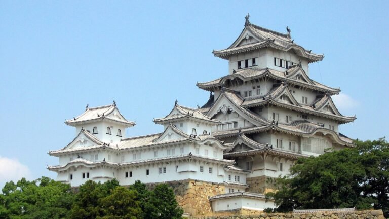 The white main keep of Himeji Castle seen from the castle grounds, surrounded by trees