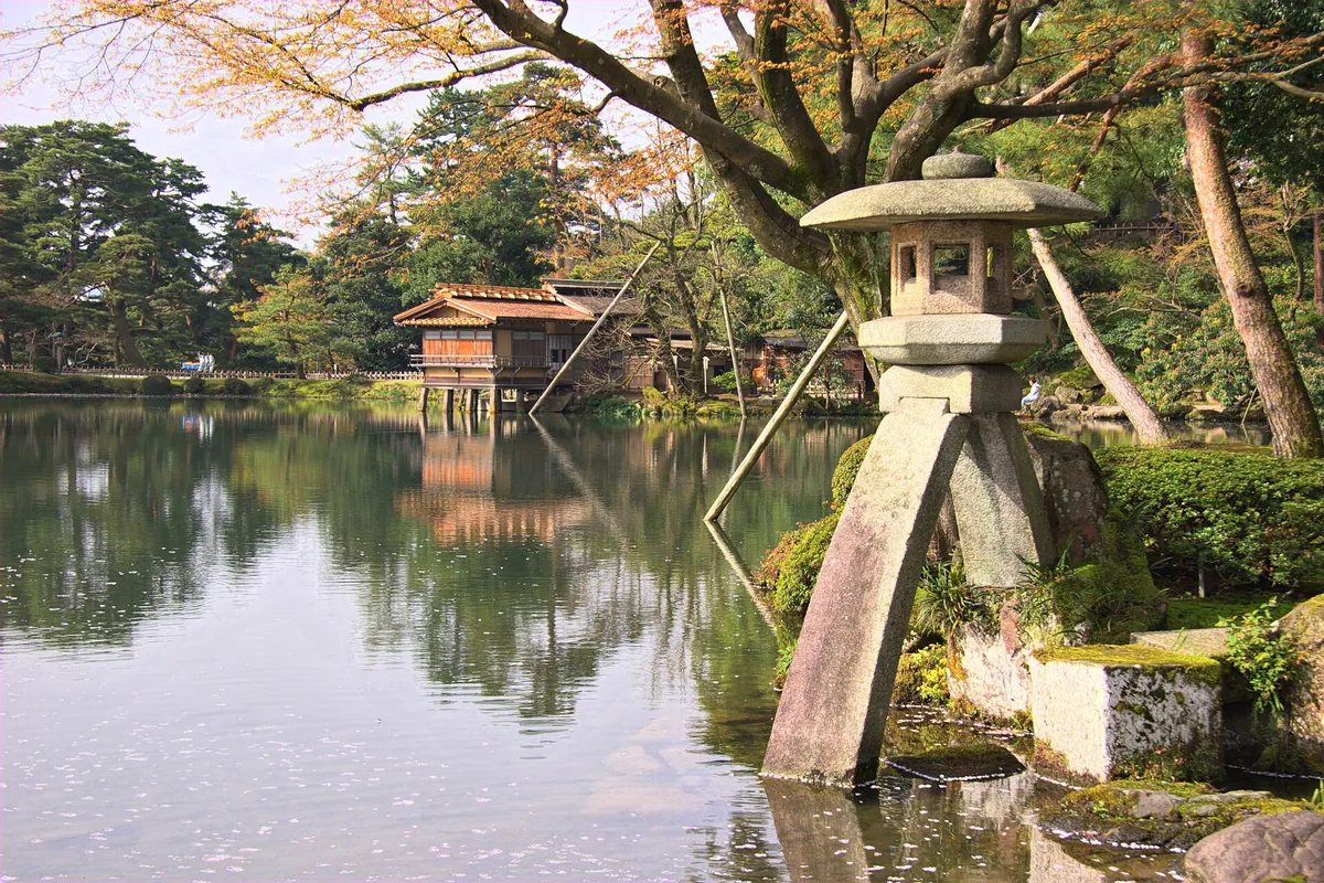 A stone lantern standing in a pond at Kenrokuen Garden in Kanazawa, surrounded by trees