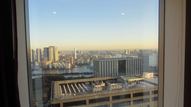 Tokyo hotel room with a bed near a large window overlooking the city skyline and bay