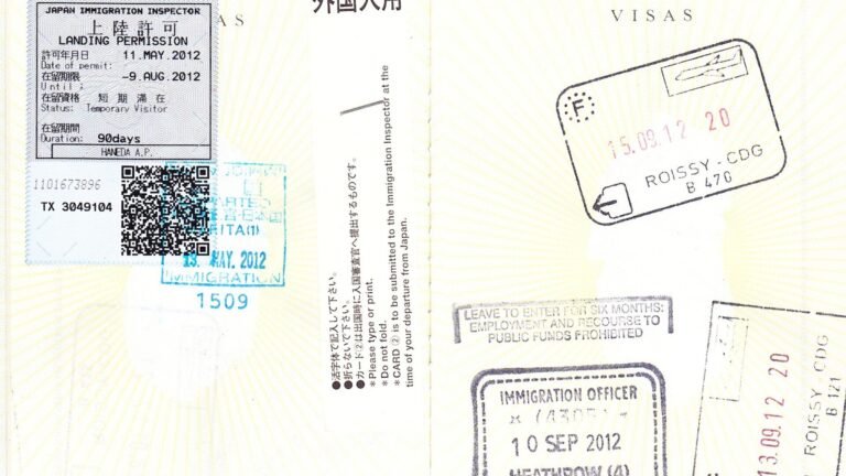 An open passport page with a Japanese landing permission sticker, a QR code, and French and UK immigration stamps