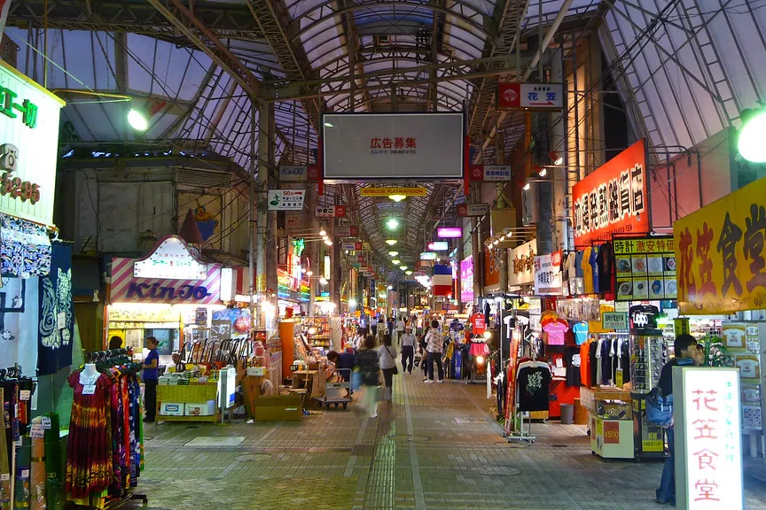 A night-time arcade on Kokusai Street in Naha lined with souvenir shops and crowds of visitors