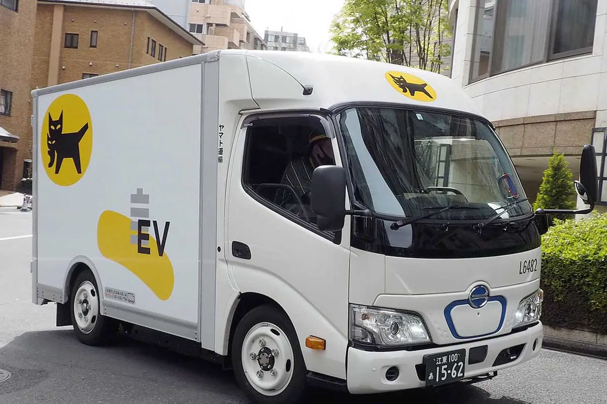 Yamato Transport delivery truck with the black cat logo and an EV badge, parked on a city street with a driver inside