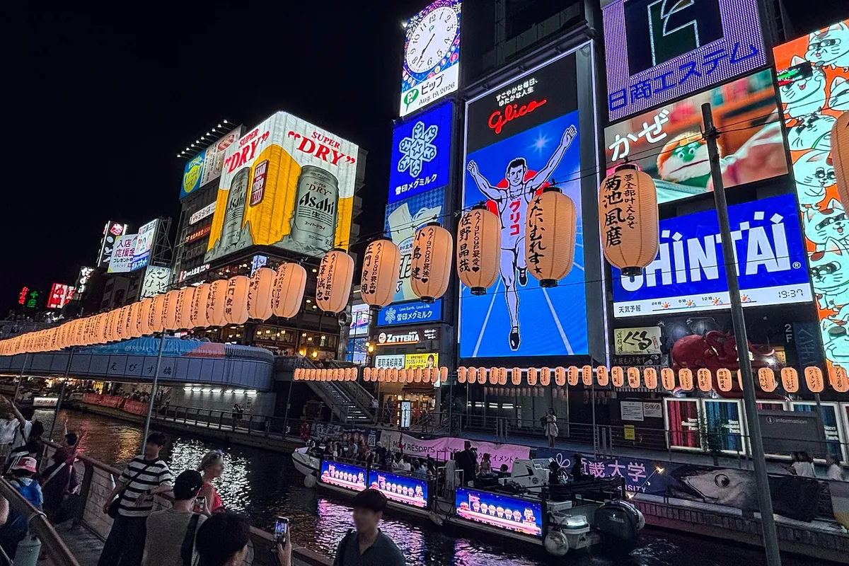 The Dotonbori canal in Osaka at night lined with illuminated signboards, lanterns, and the Glico sign