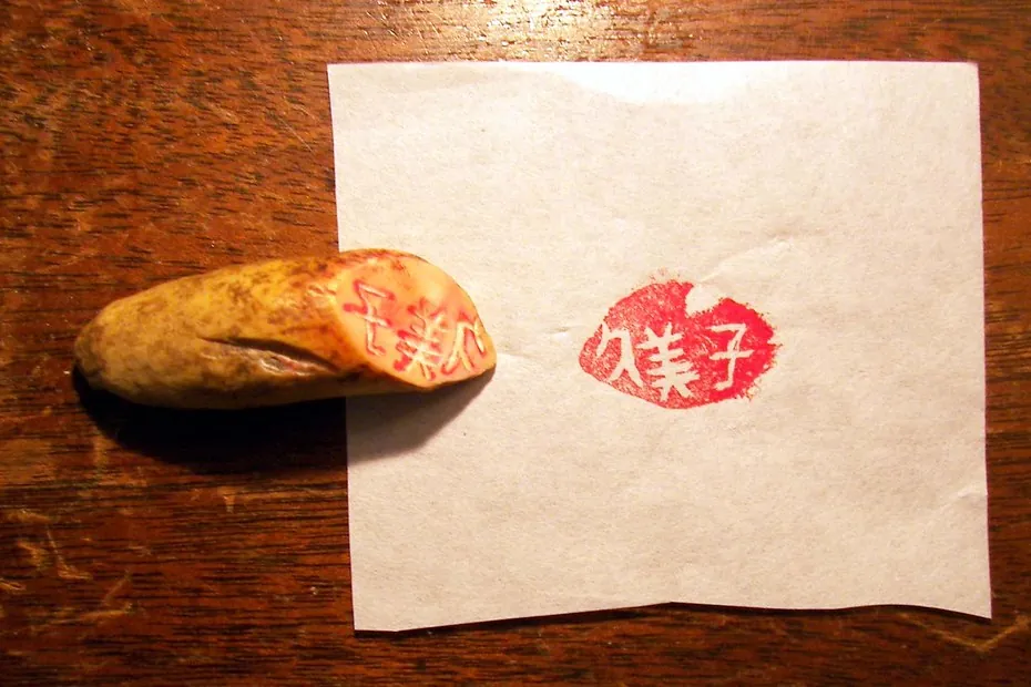 刻在豆荚形材料上的印章，旁边是它在纸上盖出的红色印迹