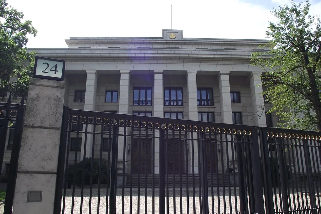 Embassy of Japan building in Berlin with columns, a gold emblem on the roof, a flagpole and an address plate reading 24