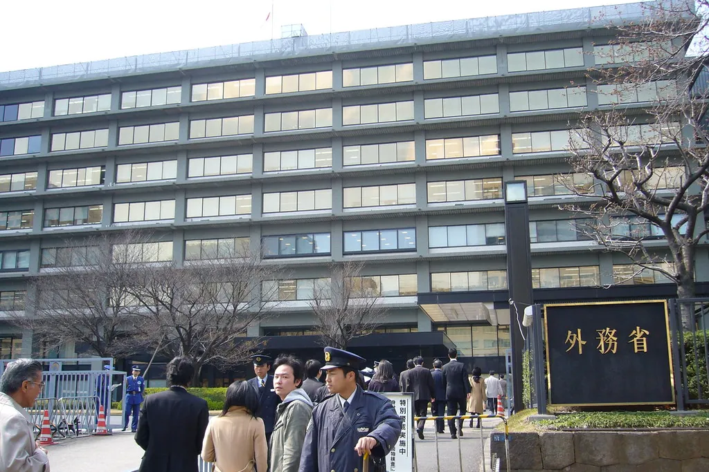 People gathered outside a building in Kasumigaseki, Tokyo with a nameplate reading Gaimusho (Ministry of Foreign Affairs)