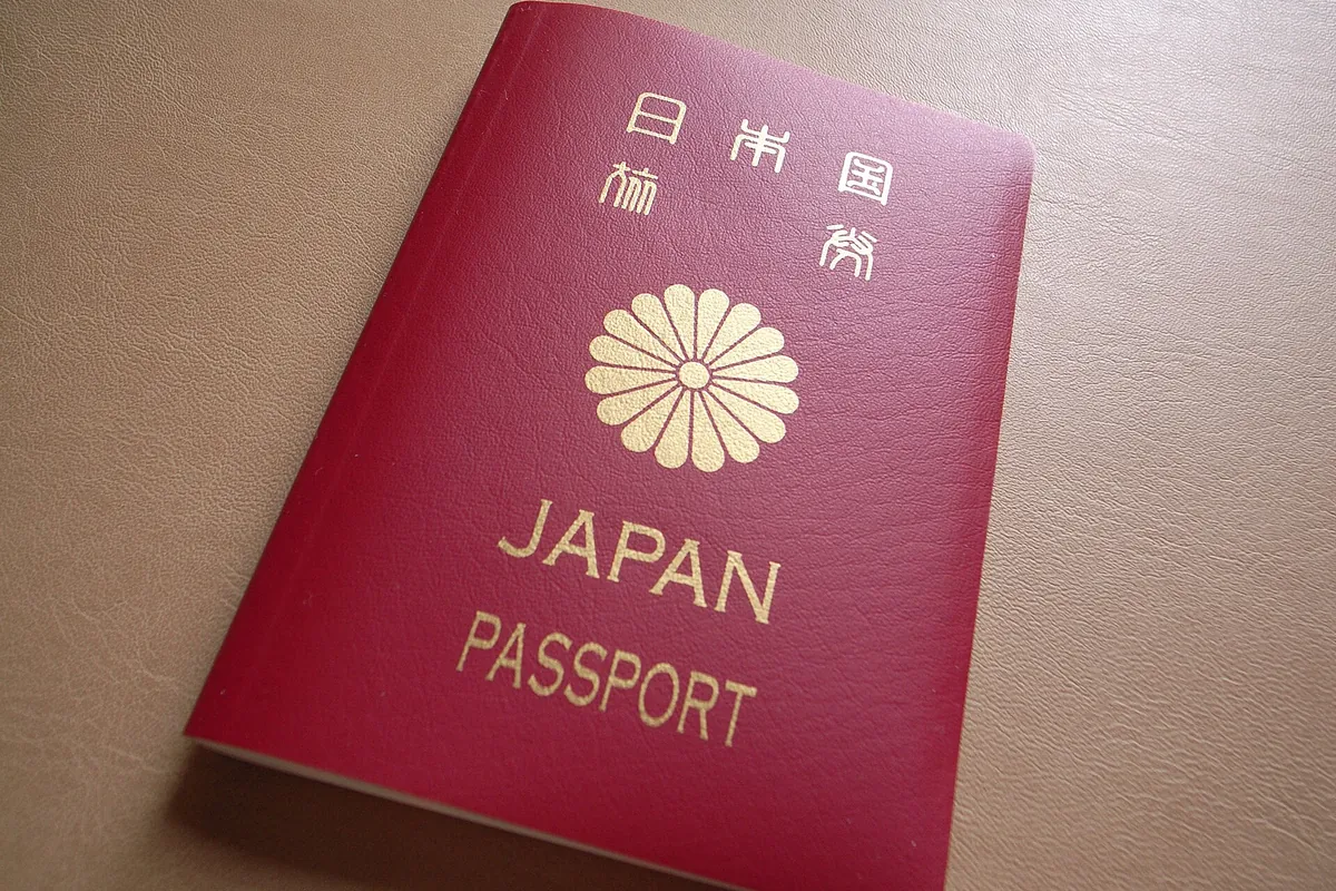A crimson Japanese passport cover with a gold chrysanthemum crest and JAPAN PASSPORT text