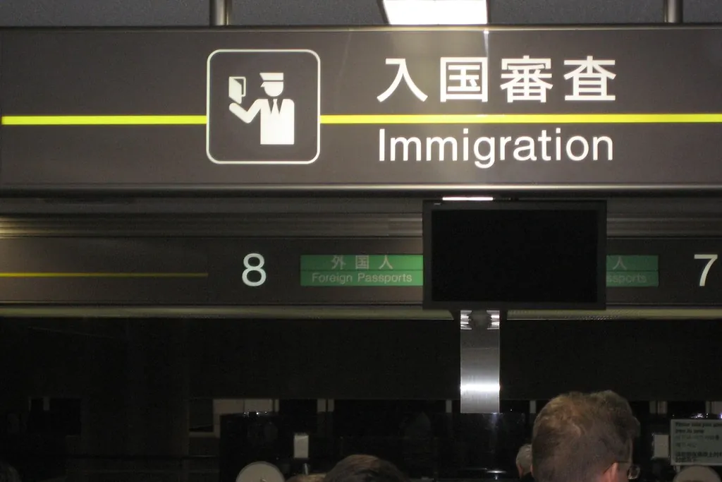 An Immigration sign in Japanese and English above numbered airport counters with a Foreign Passports sign