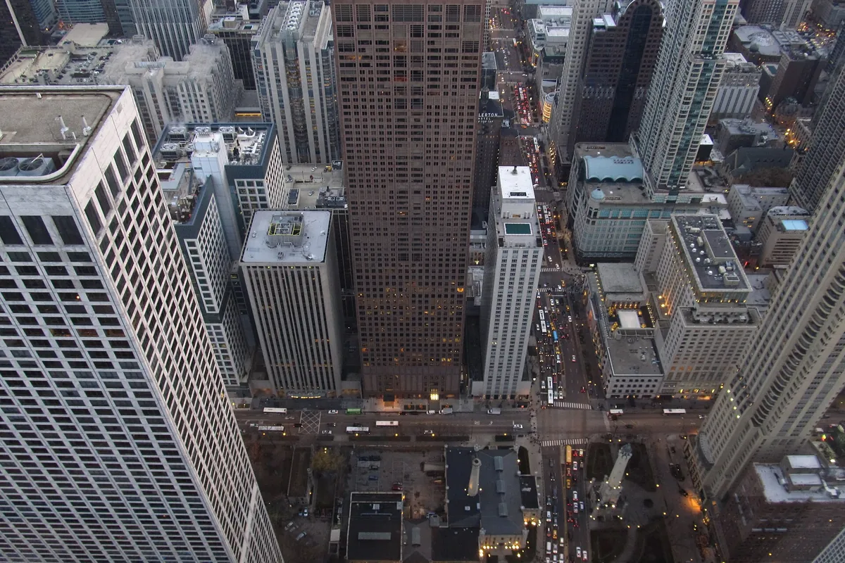 Aerial view down a Chicago street lined with skyscrapers and traffic, seen from an observatory