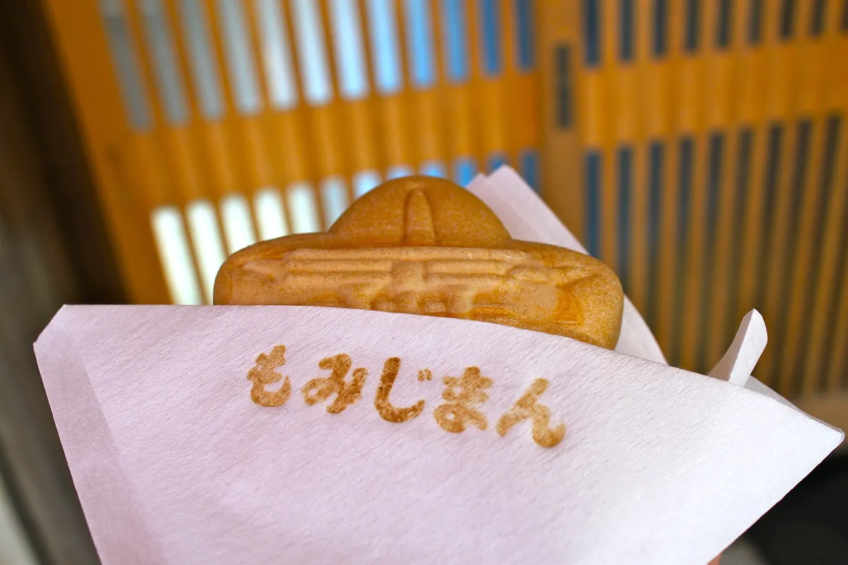 紙に包まれたもみじの葉の形のもみじ饅頭のクローズアップ。宮島のおみやげ菓子
