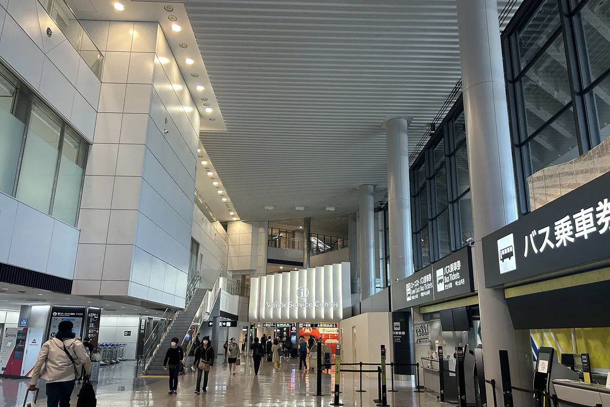 기둥과 천장 안내판, 버스 승차권 카운터가 있는 나리타 공항 제1터미널 도착 로비 내부