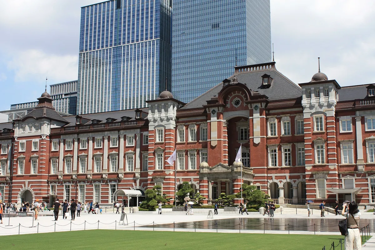 Red-brick Marunouchi building of Tokyo Station seen across a lawn with pedestrians in front