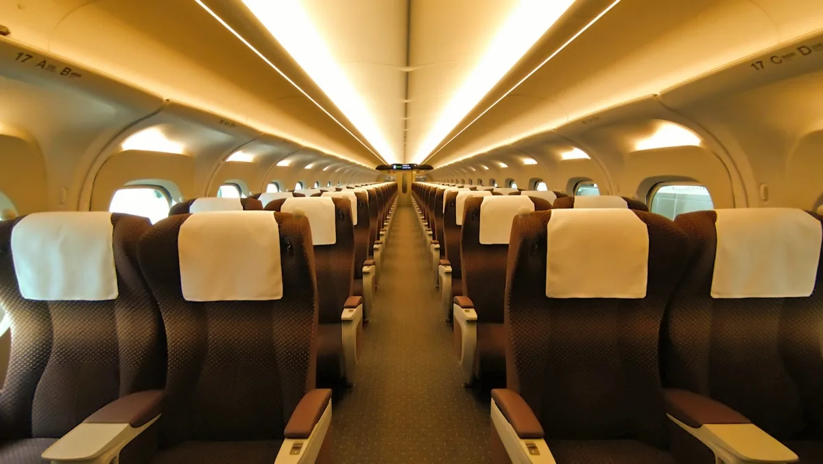 Green Car interior of a Tokaido Shinkansen N700S, with brown seats in rows of two on each side of the aisle, in 2022