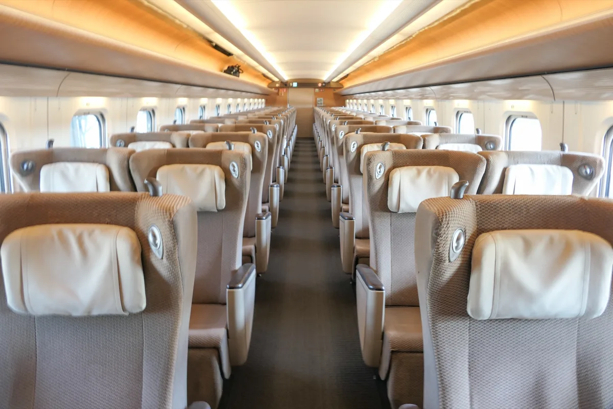 Green Car interior of a JR East E5 series Shinkansen, with beige seats in rows of two on each side, in 2023