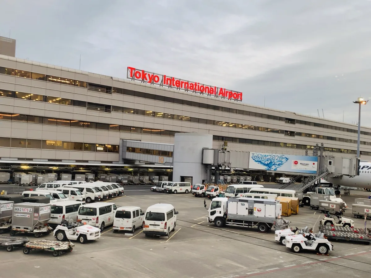 エプロン側から見た羽田空港のターミナルビル。赤い Tokyo International Airport の看板と空港の作業車が見える。