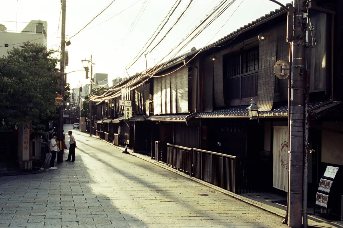 A quiet stone-paved street in Gion, Kyoto, lined with dark wooden machiya townhouses, in 2024