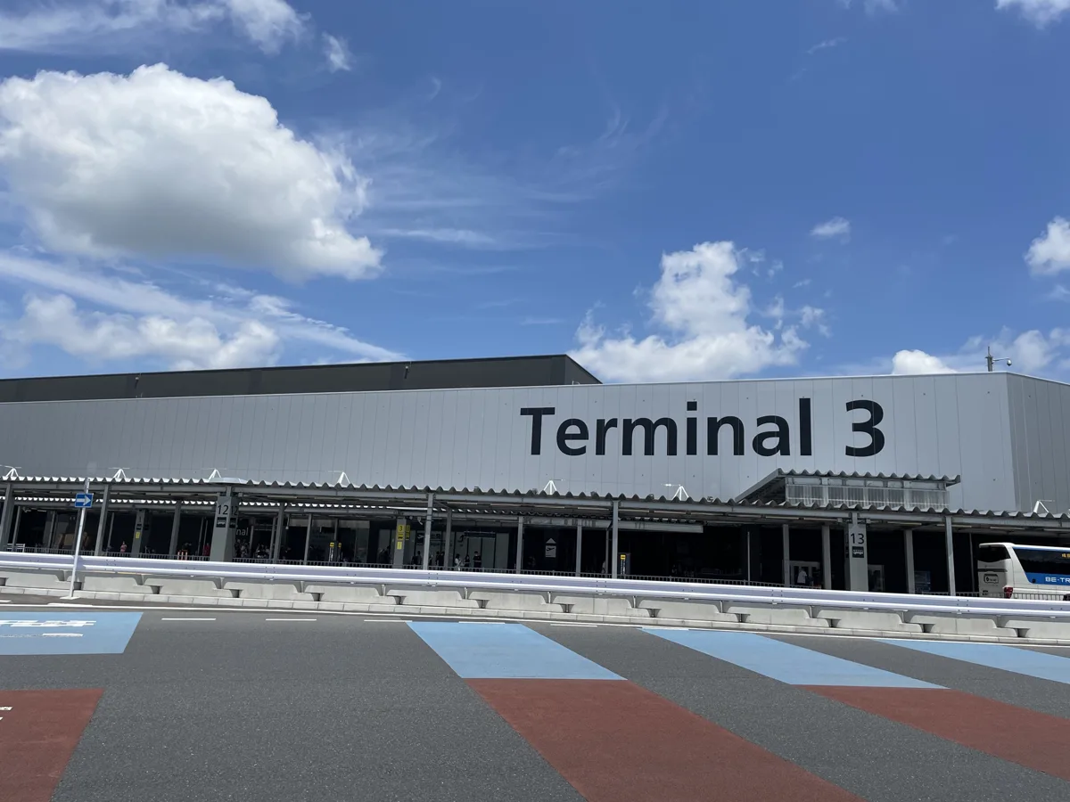 The outside of Narita Airport Terminal 3 with the large Terminal 3 sign and the coloured walking lanes in front, in 2024