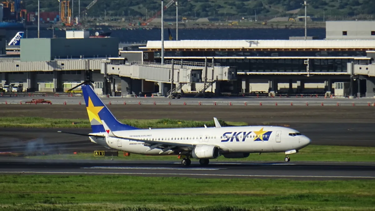 A Skymark Airlines Boeing 737-800 in white livery with a blue and yellow star tail on the runway at Haneda Airport, in 2026